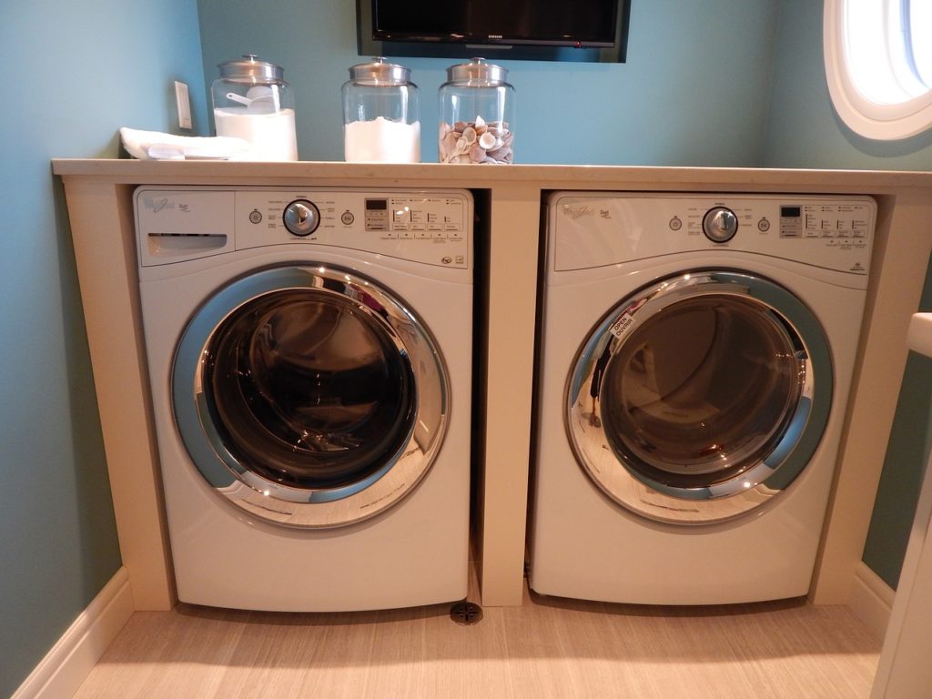 Washing machine and dryer in cabinet in laundry room with detergent jars on top
